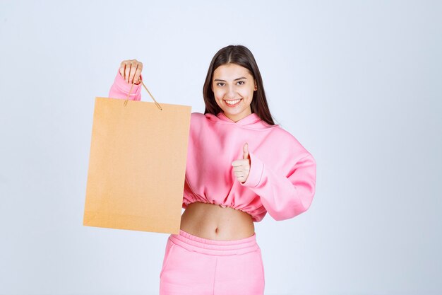 Girl holding a cardboard shopping bag and feeling excited. 