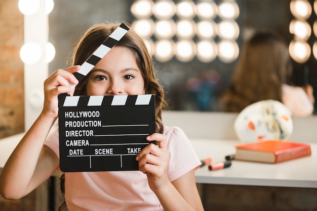 Girl holding clapperboard in front of her mouth