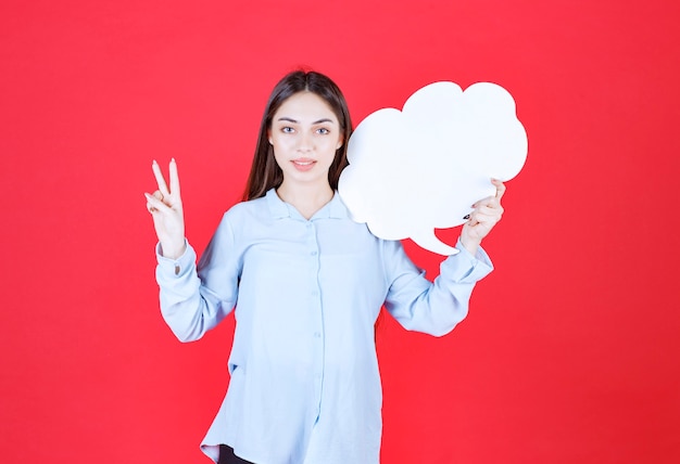 Girl holding a cloud shape info board and showing positive hand sign. 