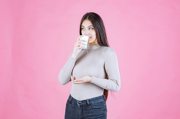 コーヒーカップを持ってそれを飲む女の子