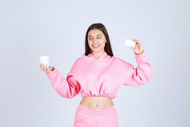 Girl holding a coffee cup in one hand and presenting her business card in another hand