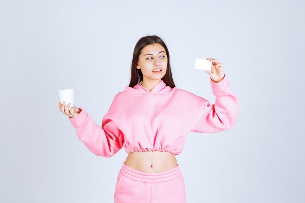 Girl holding a coffee cup in one hand and presenting her business card in another hand