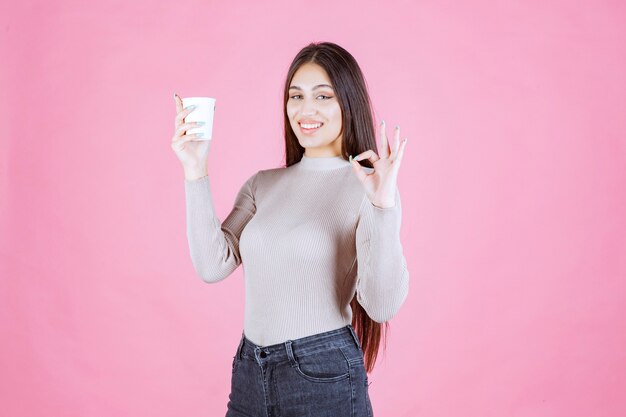 Girl holding a coffee cup and pointing to good taste