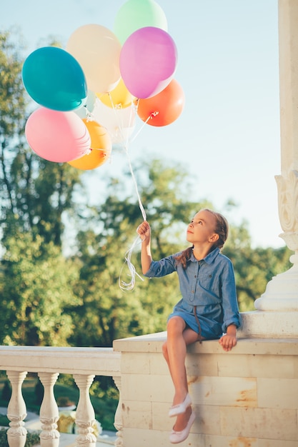 Girl holding colorful balloons looking to them