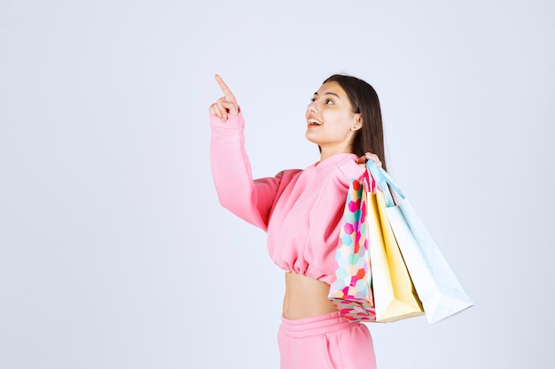 Ragazza che tiene i sacchetti della spesa variopinti indietro alla sua spalla.