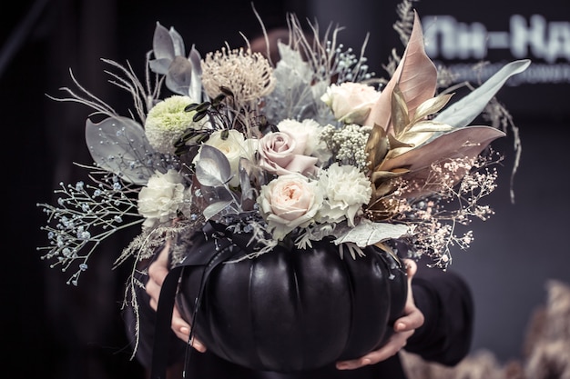 Girl holding a flower arrangement in a pumpkin.