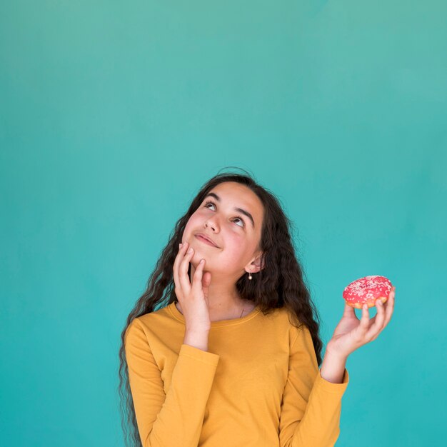 Girl holding a glazed doughnut with copy space