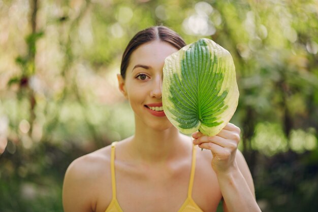 Девушка держит зеленый лист возле ее лица