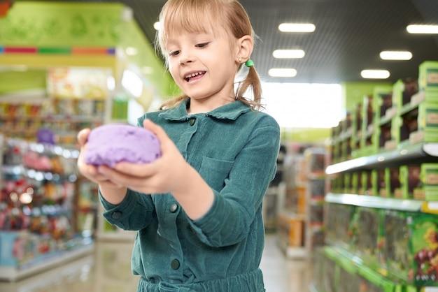 Free photo girl holding in hands violet kinetic sand, posing at camera.