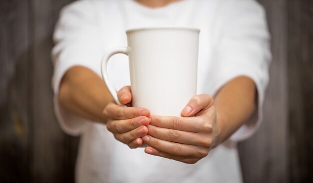 the girl holding a large Cup on wood