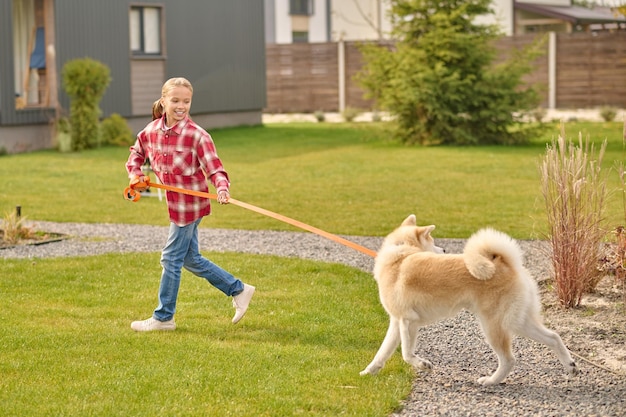 Girl holding leash running looking at dog