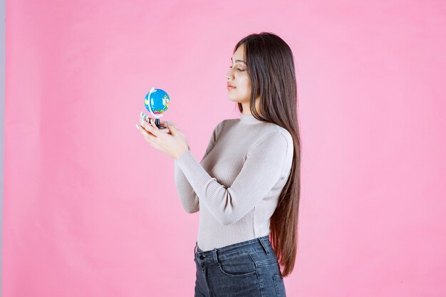 Girl holding a mini globe and studying it attentively