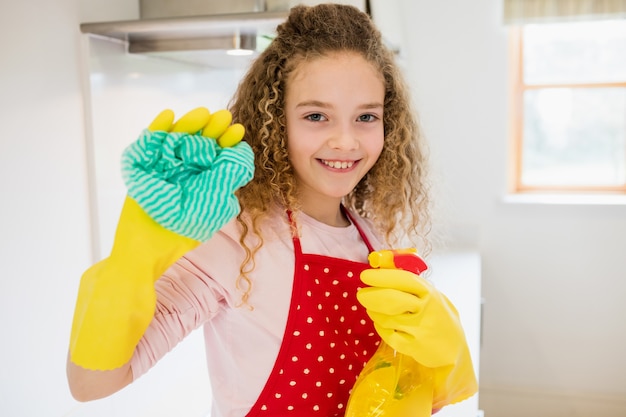 Girl holding napkin and spray bottle in kitchen