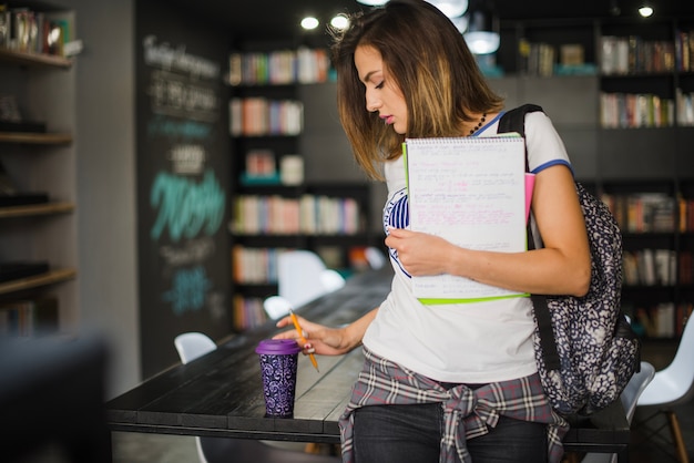 Girl holding notebooks grabbing cup