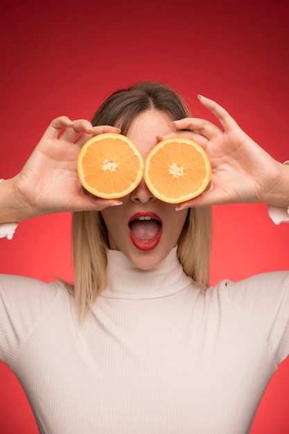 Free photo girl holding orange slices  over her eyes