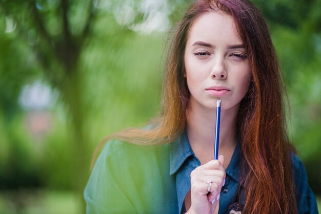 Girl holding pencil focusing outside