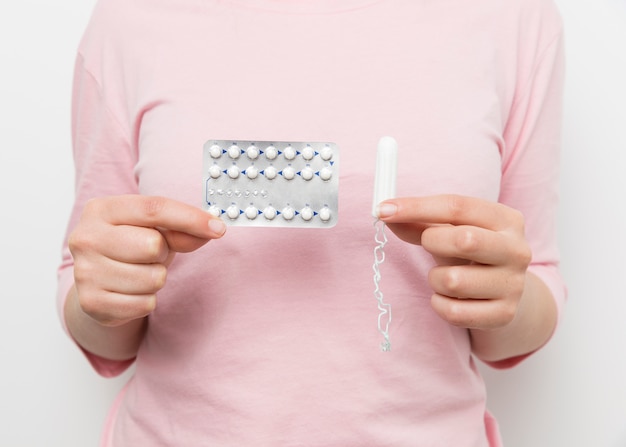 Girl holding pill blister and tampon