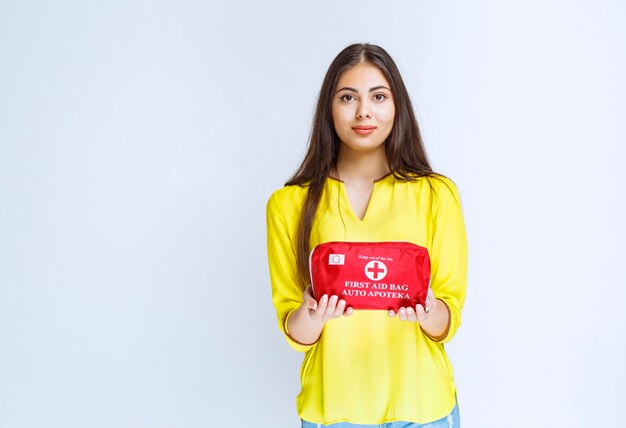 Girl holding and promoting a red first aid kit.