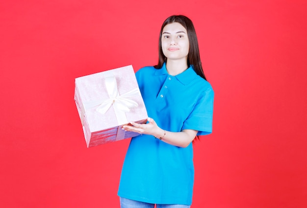 Girl holding a purple gift box wrapped with white ribbon