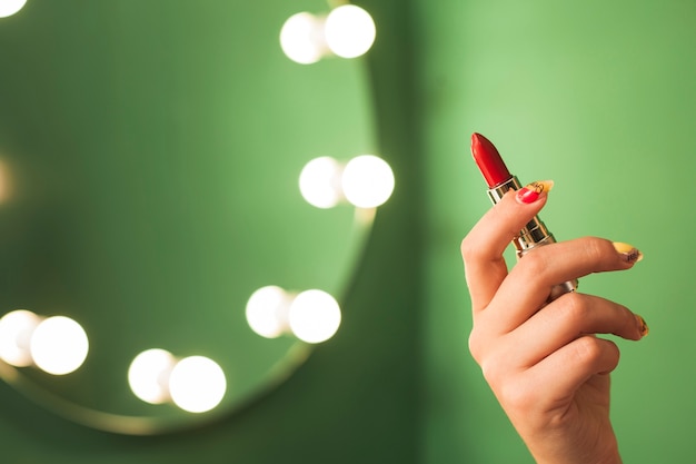 Girl holding red lipstick in front of a mirror