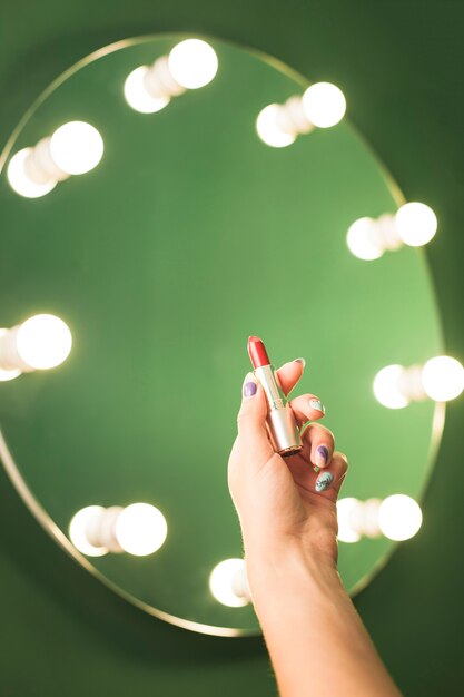 Girl holding red lipstick in front of a mirror