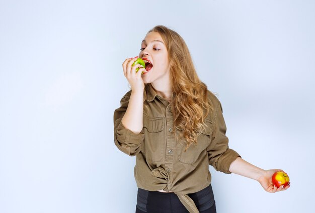 赤桃を持って青リンゴを噛む少女。