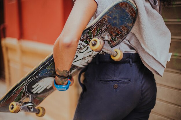 Girl holding skateboard walking outside