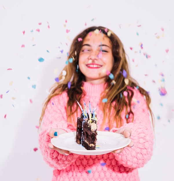 Девушка, проведение кусок шоколадного торта, окруженный конфетти