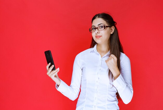 Girl holding a smartphone and giving happiness poses.