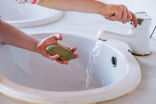 Girl holding soap while washing hand in washbasin