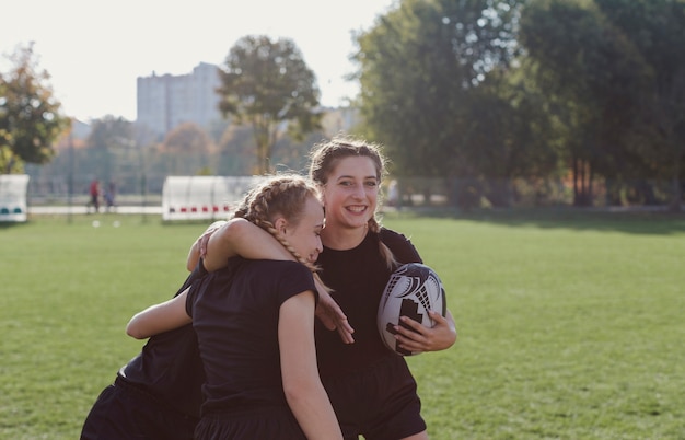 サッカーボールを押しながら彼女のチームの仲間を抱きしめる少女