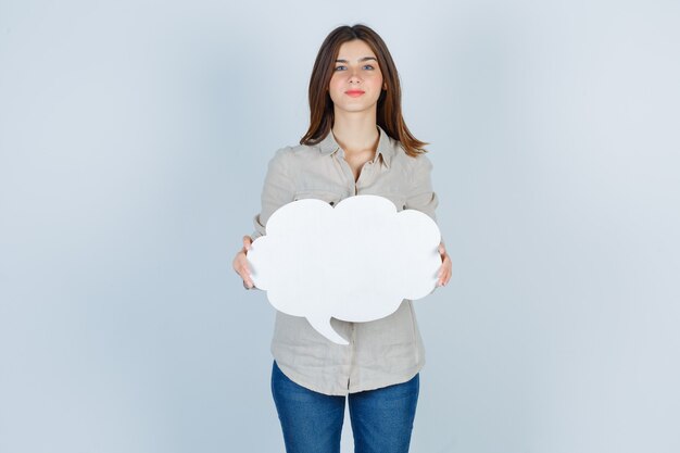 girl holding speech bubble in shirt, jeans and looking hopeful.