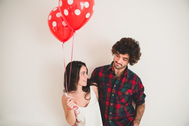 Девочка держит два воздушных шаров со своим парнем рядом