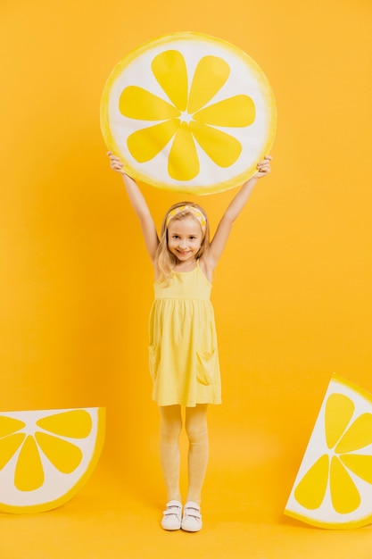 Free photo girl holding up lemon slice decoration