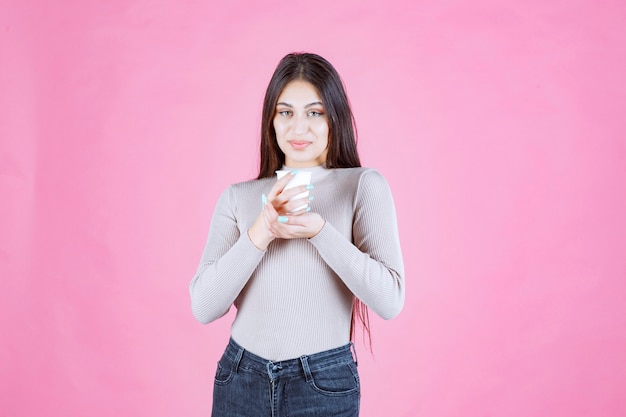 Girl holding a white disposable coffee cup, promoting it or smelling the fresh coffee