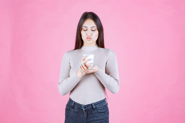 Girl holding a white disposable coffee cup, promoting it or smelling the fresh coffee