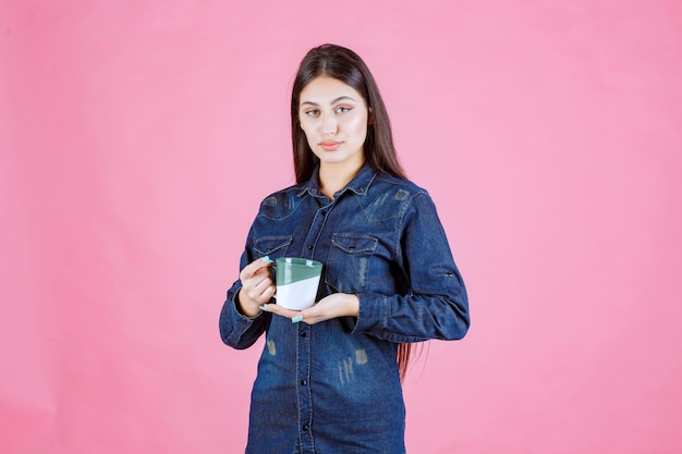 Girl holding a white green coffee mug and smelling