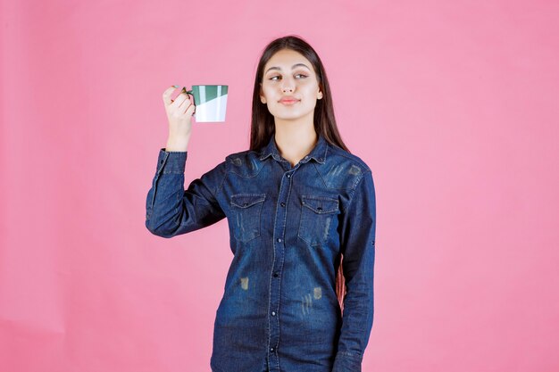 Girl holding a white green coffee mug and smelling