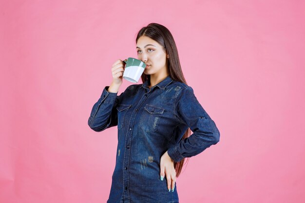 Ragazza che tiene una tazza di caffè verde bianca e un odore