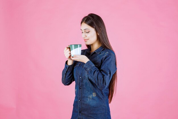 Girl holding a white green coffee mug and smelling