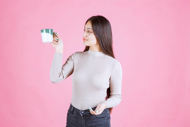 Girl holding a white green color coffee mug and feeling positive