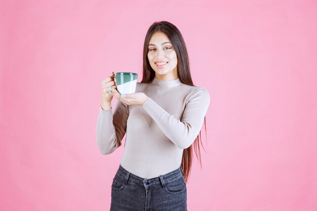 白緑色のコーヒーマグを保持し、前向きな気持ちの女の子