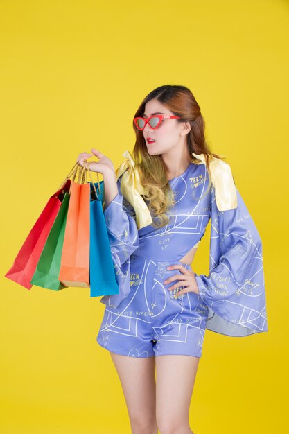 The girl holds a fashion shopping bag and holds a smart card on a yellow background.