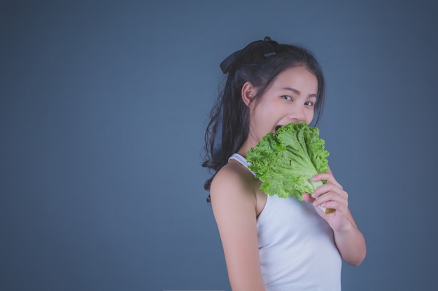 Girl holds the vegetables on a gray background.