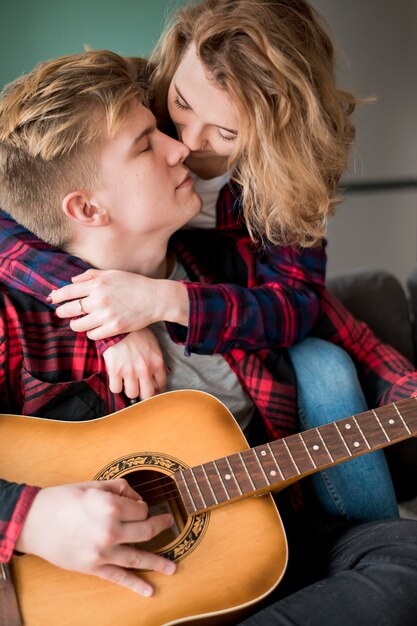 Girl hugging boyfriend playing guitar