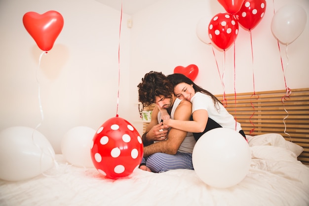 Free photo girl hugging her boyfriend from behind on a bed