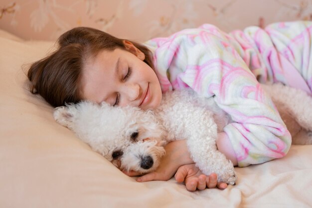 Девушка обнимает собаку в постели во время сна