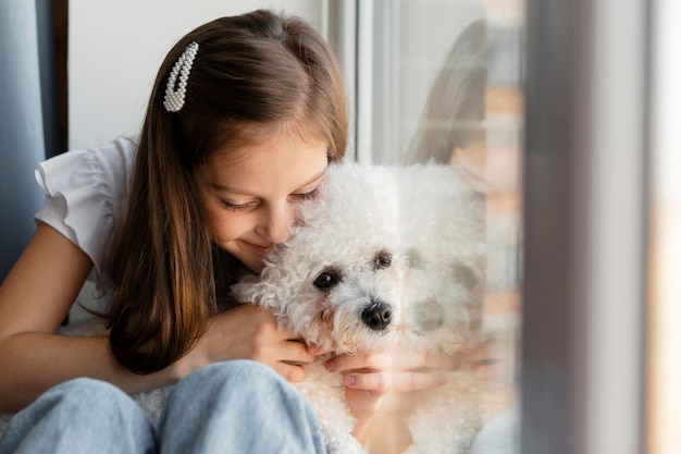 窓際で犬を抱きしめる少女