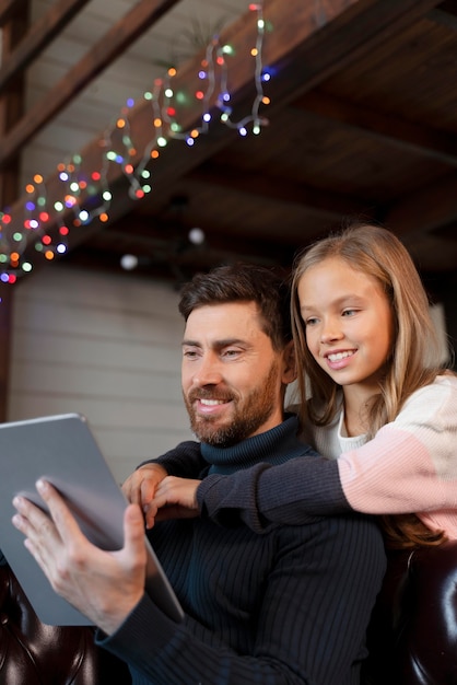 Free photo girl hugging her father while holding a tablet