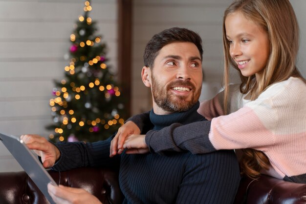 Girl hugging her father while holding a tablet